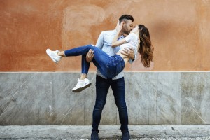 Carefree couple in love kissing in front of a wall outdoors