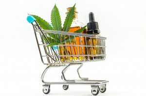 Supermarket trolley with marijuana leafs and medical cannabis oil cbd