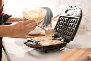 Woman preparing homemade waffles in kitchen